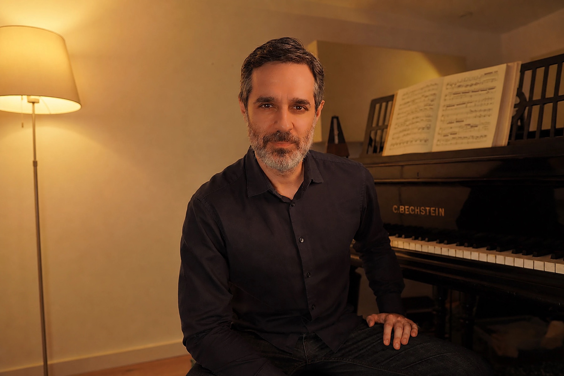Felipe Scagliusi sentado ao lado do piano, em sua sala de estudo
